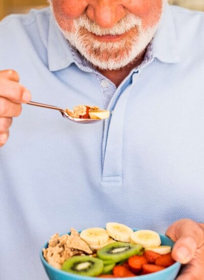 Smiling elderly man holding a bowl of fresh and dried fruits. healthy eating at breakfast Smiling elderly man holding a bowl of fresh and dried fruits. healthy eating at breakfast